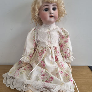 Vintage doll in a floral dress on a plain background