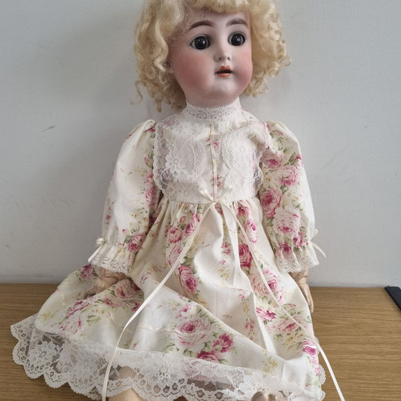 Vintage doll in a floral dress on a plain background